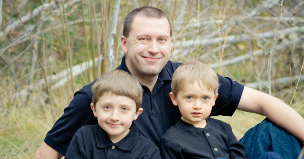 father posing with two sons for photo in the park