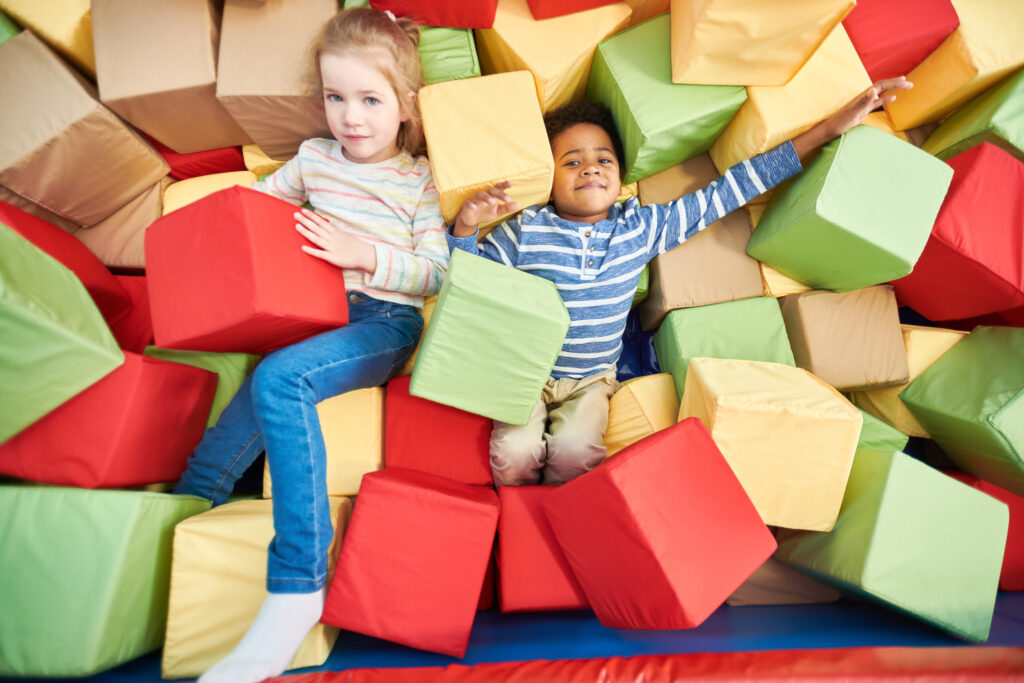 Colorful above view portrait of two happy little kids playing in foam pit of trampoline center